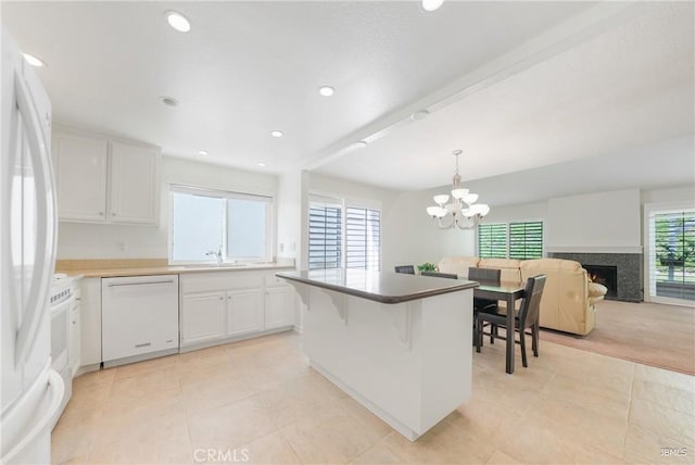 kitchen featuring white appliances, white cabinetry, a kitchen island, and a premium fireplace