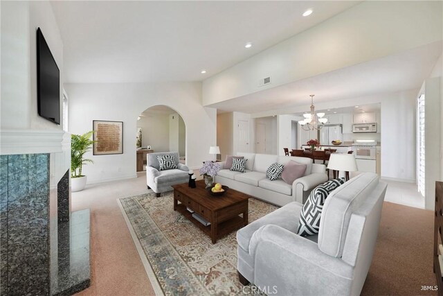 living area with visible vents, arched walkways, light colored carpet, a chandelier, and recessed lighting