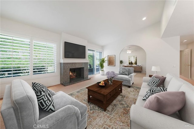 carpeted living area featuring high vaulted ceiling, recessed lighting, arched walkways, and a high end fireplace