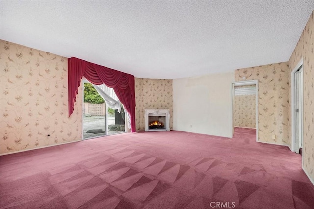 unfurnished living room with wallpapered walls, carpet, and a textured ceiling