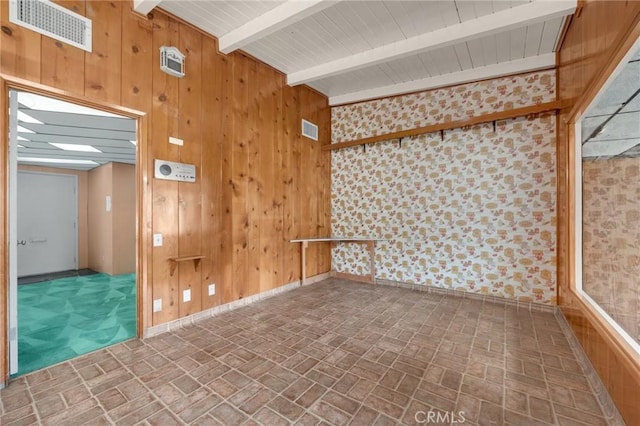 empty room featuring wood walls, visible vents, and brick patterned floor