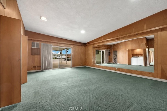 spare room featuring carpet flooring, vaulted ceiling, wood walls, and washing machine and clothes dryer