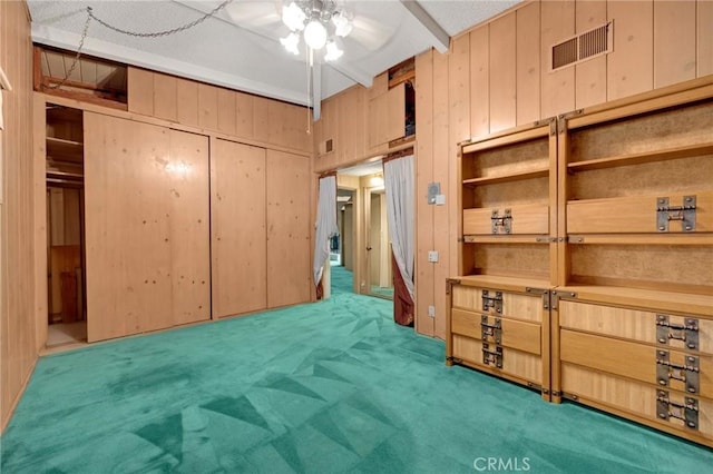 carpeted bedroom with wooden walls, visible vents, and a closet