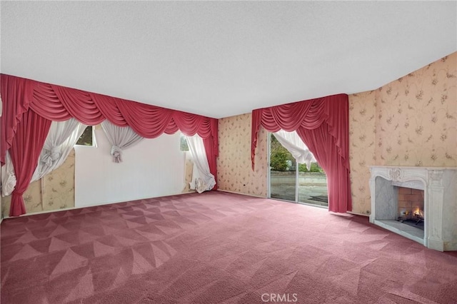 unfurnished living room with carpet flooring, a high end fireplace, and wallpapered walls