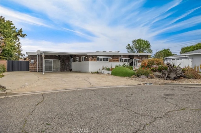 view of front of home featuring driveway, an attached carport, fence, and a gate