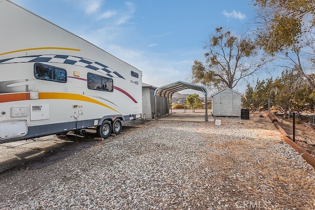 exterior space with gravel driveway, a shed, fence, and a detached carport