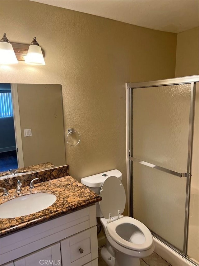 full bath with a textured wall, vanity, a shower stall, and toilet