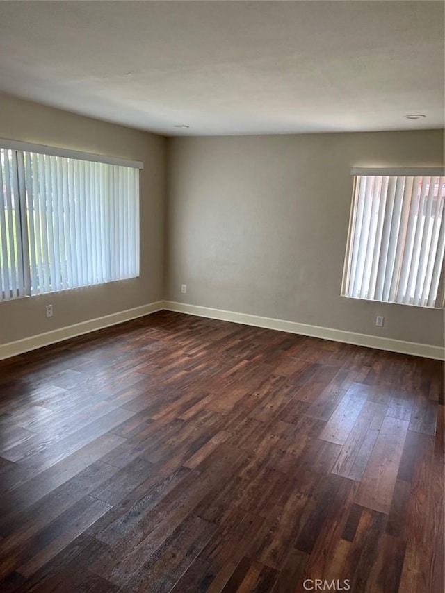 empty room featuring dark wood-style flooring and baseboards