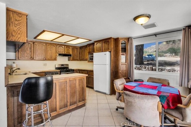 kitchen featuring visible vents, a peninsula, stainless steel appliances, under cabinet range hood, and a sink