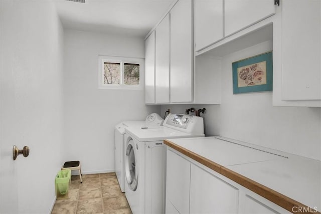 clothes washing area with cabinet space, washing machine and dryer, and baseboards