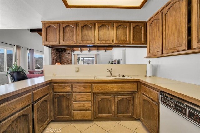 kitchen with brown cabinets, light countertops, light tile patterned flooring, a sink, and dishwasher