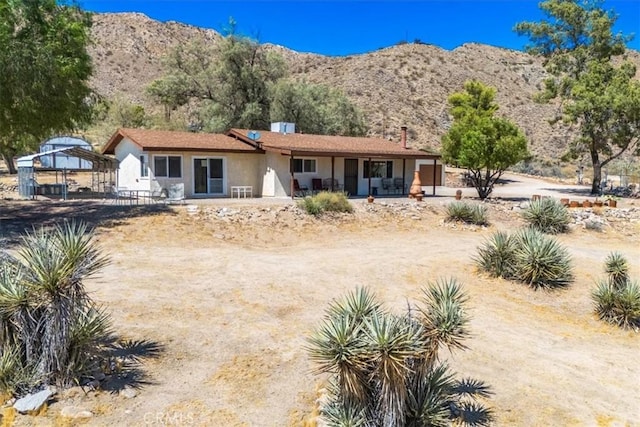 view of front of home featuring dirt driveway, a gazebo, a mountain view, and stucco siding