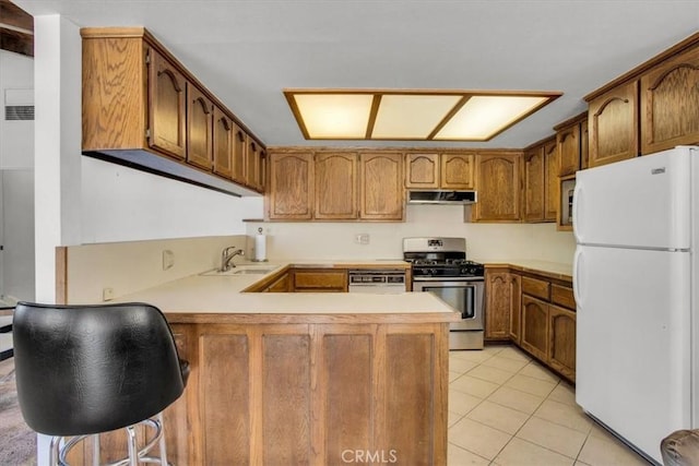 kitchen featuring light tile patterned floors, appliances with stainless steel finishes, a peninsula, light countertops, and a sink