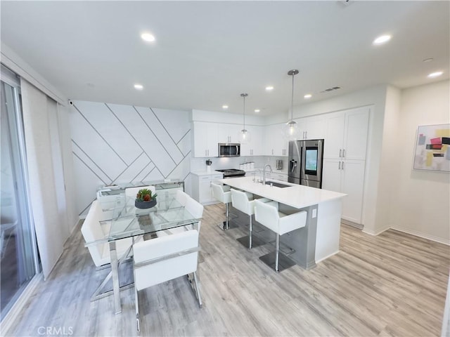 kitchen featuring light countertops, stainless steel appliances, light wood-style floors, white cabinetry, and a sink