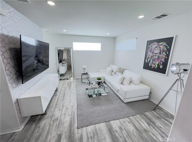 living room featuring recessed lighting, wood finished floors, visible vents, and baseboards