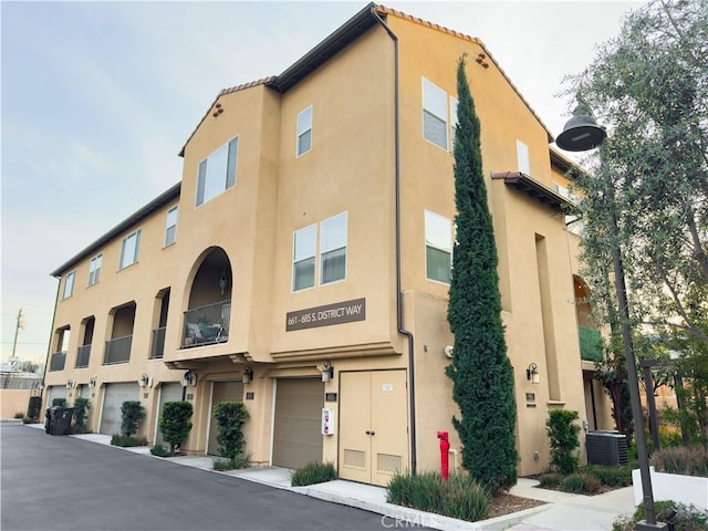 view of property featuring a garage and central AC unit