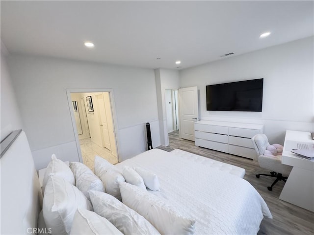 bedroom featuring wood finished floors, recessed lighting, visible vents, and ensuite bathroom