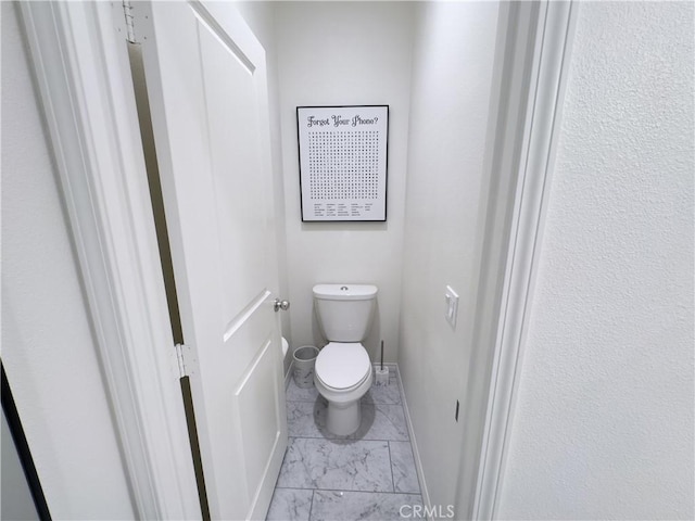 bathroom featuring toilet, baseboards, and marble finish floor