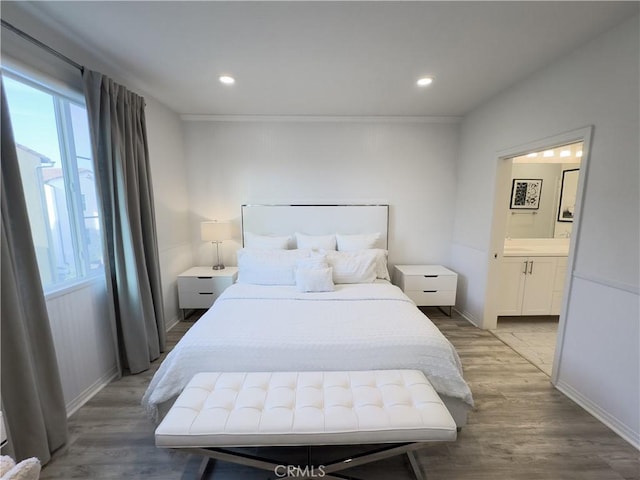 bedroom featuring light wood-type flooring, multiple windows, and connected bathroom