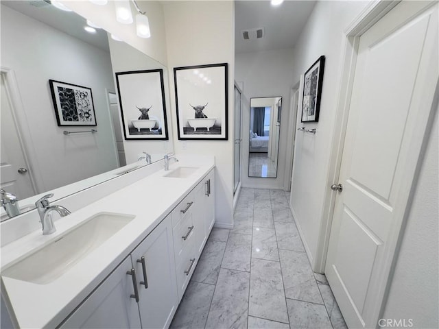 ensuite bathroom featuring visible vents, baseboards, marble finish floor, and a sink