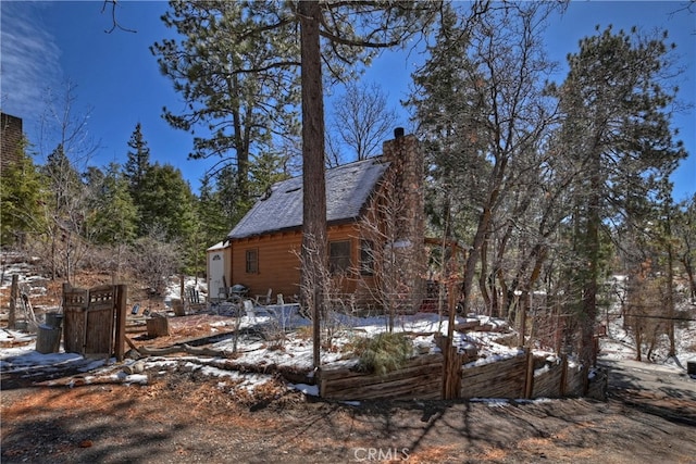 view of snow covered exterior featuring a vegetable garden and a chimney