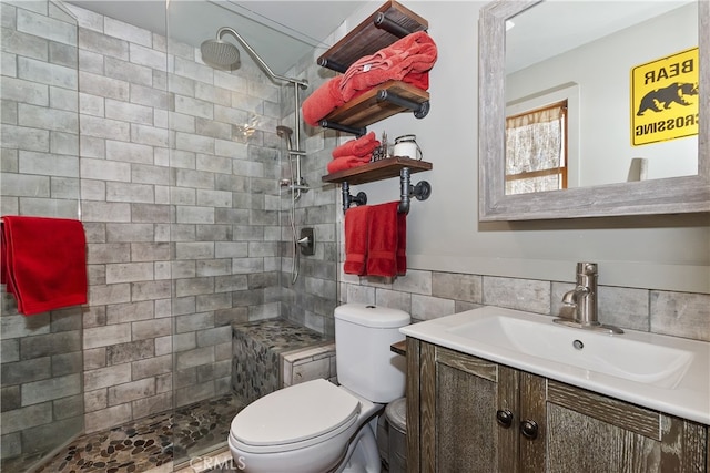 full bathroom featuring toilet, a tile shower, tile walls, and vanity