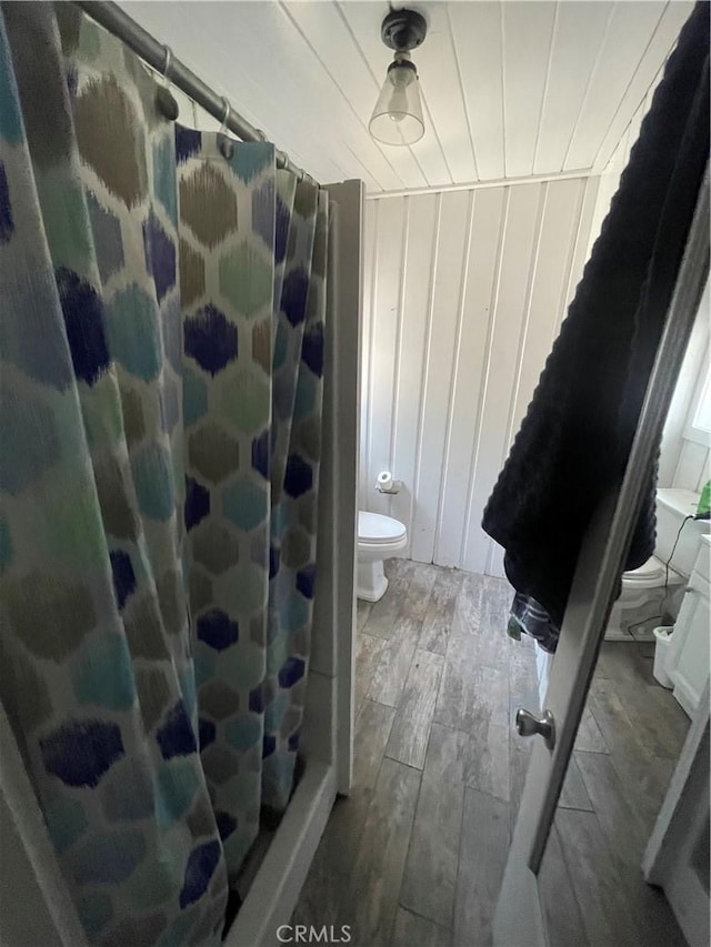 bathroom featuring curtained shower, wooden ceiling, wood finished floors, and toilet