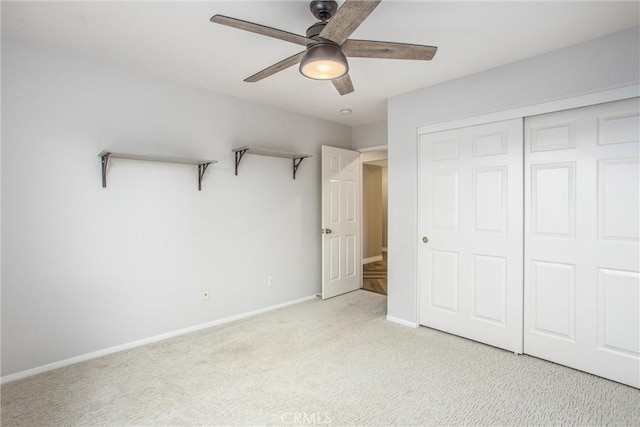 unfurnished bedroom with baseboards, ceiling fan, a closet, and light colored carpet