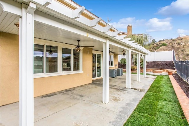 view of patio with central AC, a fenced backyard, ceiling fan, and a fire pit