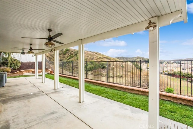 view of patio featuring ceiling fan, stairs, a mountain view, and a fenced backyard