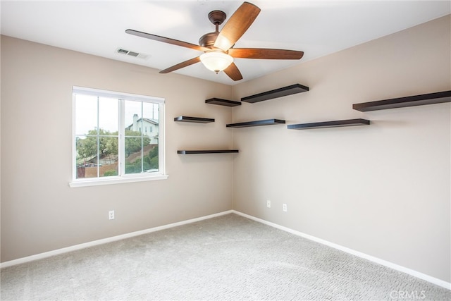 carpeted spare room featuring ceiling fan, visible vents, and baseboards