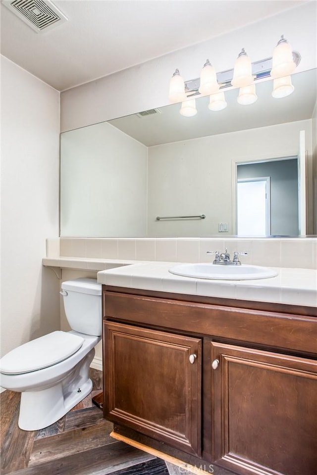 bathroom featuring toilet, visible vents, wood finished floors, and vanity