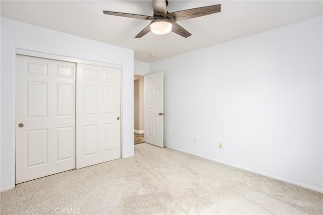 unfurnished bedroom with ceiling fan, a closet, carpet flooring, and baseboards