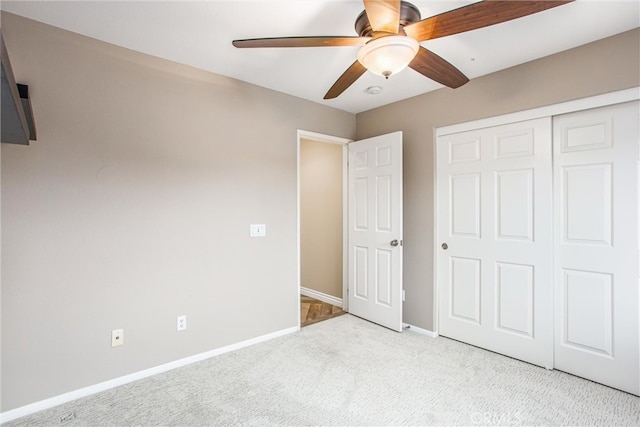 unfurnished bedroom featuring light carpet, a closet, a ceiling fan, and baseboards