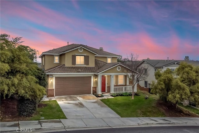 traditional home featuring an attached garage, a front lawn, concrete driveway, and stucco siding