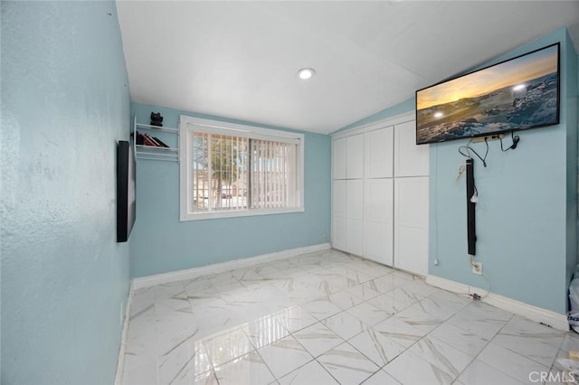 unfurnished bedroom featuring baseboards, lofted ceiling, marble finish floor, and a closet