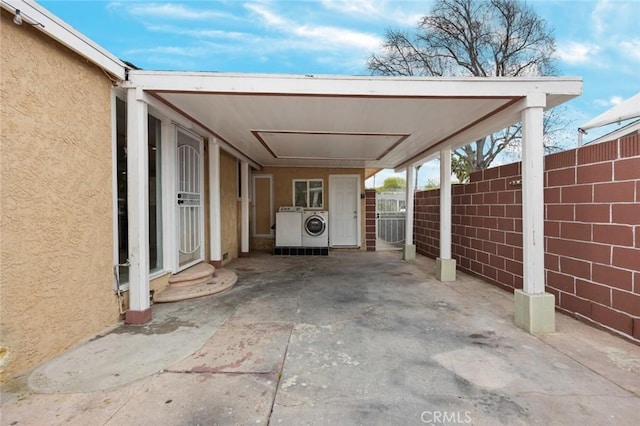 view of parking featuring a carport, independent washer and dryer, and fence