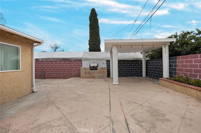 view of patio with a carport, fence, and driveway