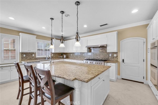 kitchen with a center island with sink, ornamental molding, backsplash, white cabinetry, and range