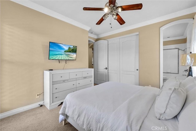 bedroom featuring crown molding, baseboards, light colored carpet, a closet, and ensuite bath