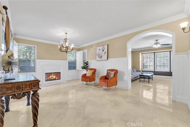 living area featuring arched walkways, a glass covered fireplace, a healthy amount of sunlight, and a decorative wall