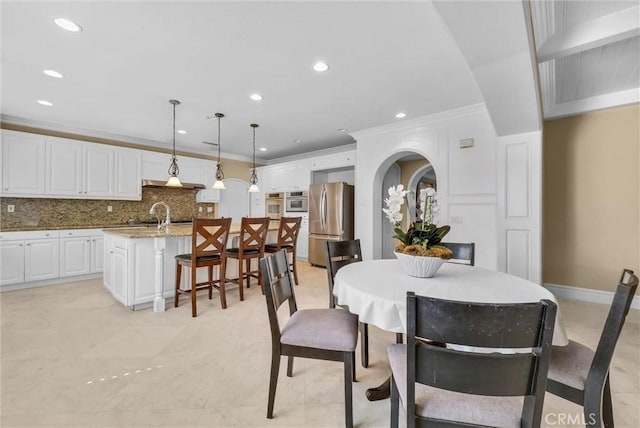 dining space with crown molding, recessed lighting, arched walkways, and baseboards