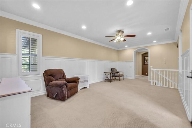 living area with recessed lighting, arched walkways, ceiling fan, ornamental molding, and light colored carpet