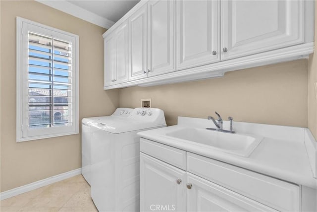 laundry room featuring a sink, washing machine and dryer, cabinet space, light tile patterned flooring, and baseboards