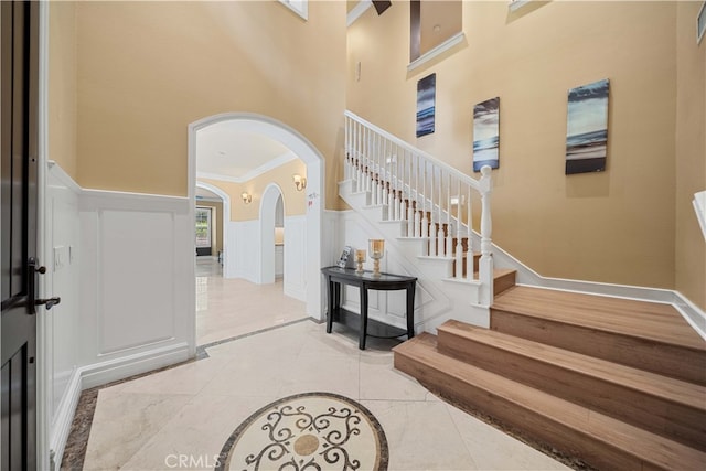 37 Shepard, Irvine, CA 92620 - entryway featuring arched walkways, wainscoting, a towering ceiling, crown molding, and a decorative wall
