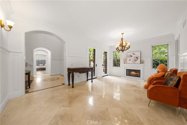 37 Shepard, Irvine, CA 92620 - living room featuring a decorative wall, a chandelier, crown molding, light marble finish floors, and a warm lit fireplace