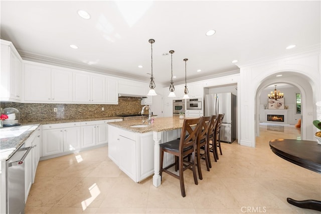 37 Shepard, Irvine, CA 92620 - kitchen with appliances with stainless steel finishes, tasteful backsplash, an island with sink, white cabinets, and ornamental molding