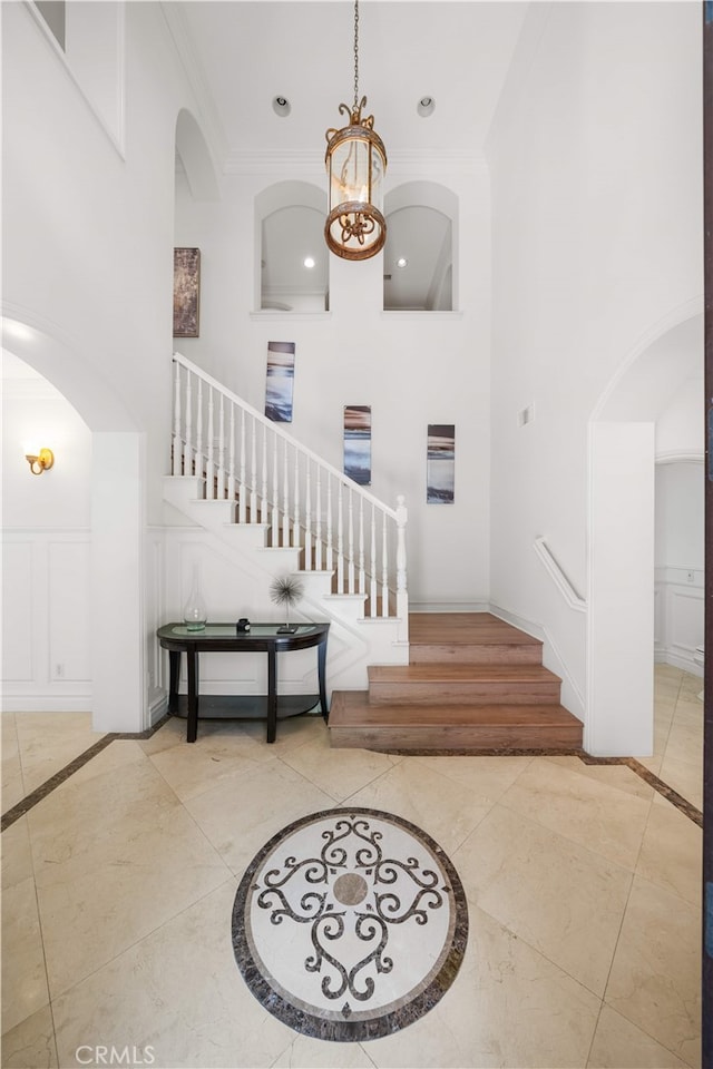 37 Shepard, Irvine, CA 92620 - entryway featuring inlaid floor details, stairway, arched walkways, a towering ceiling, and crown molding