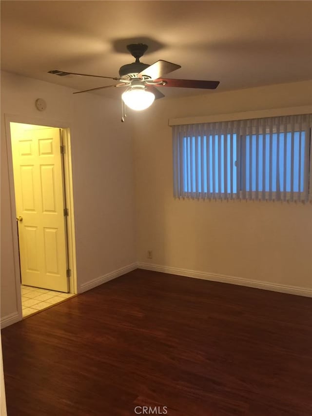 empty room featuring ceiling fan, wood finished floors, visible vents, and baseboards