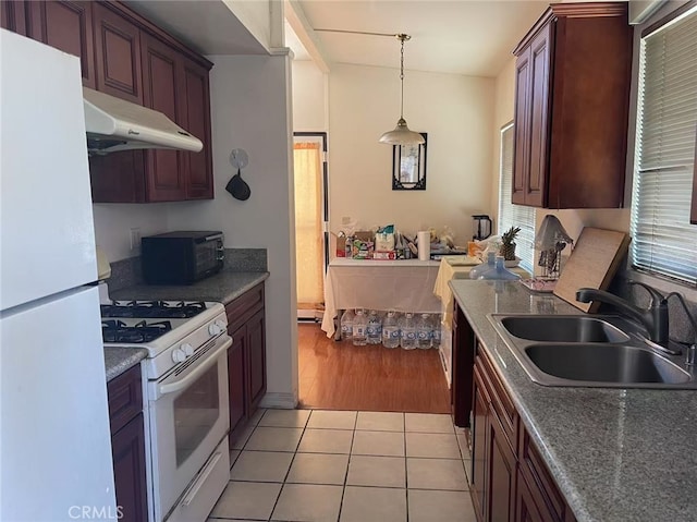 kitchen with light tile patterned floors, hanging light fixtures, a sink, white appliances, and under cabinet range hood